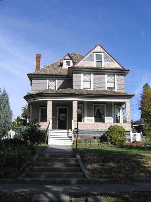 Wrap around porch with dentil trim under eave and fish scale shingled porch supports