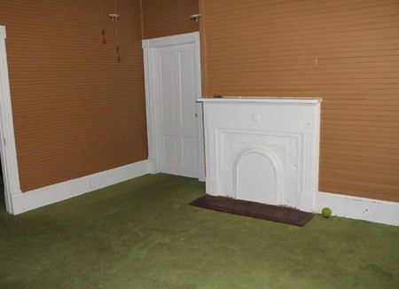 Image of interior room showing bead-board walls and fireplace